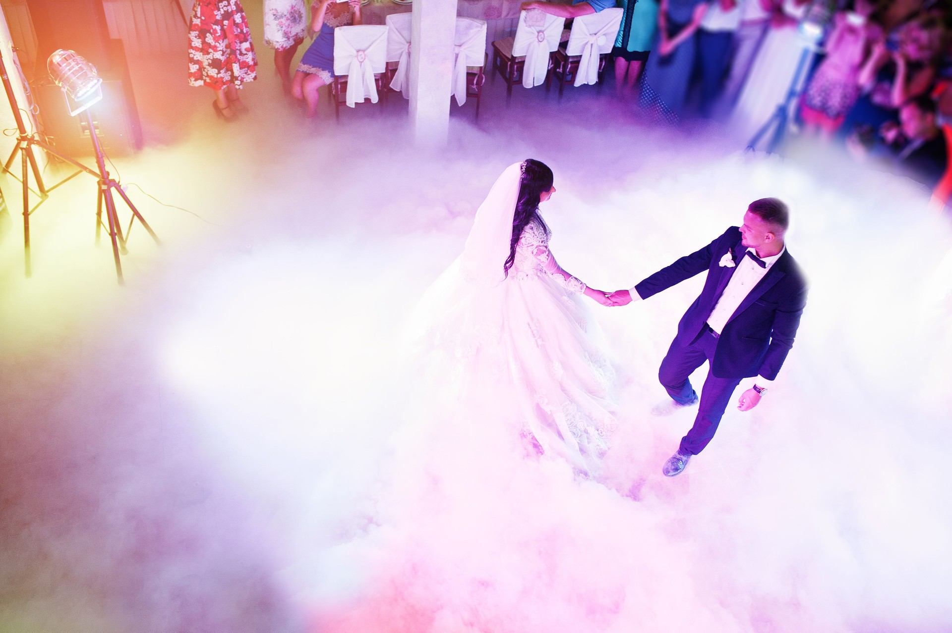 Amazing first wedding dance of newlywed with different colourful light and heavy smoke on restaurant.