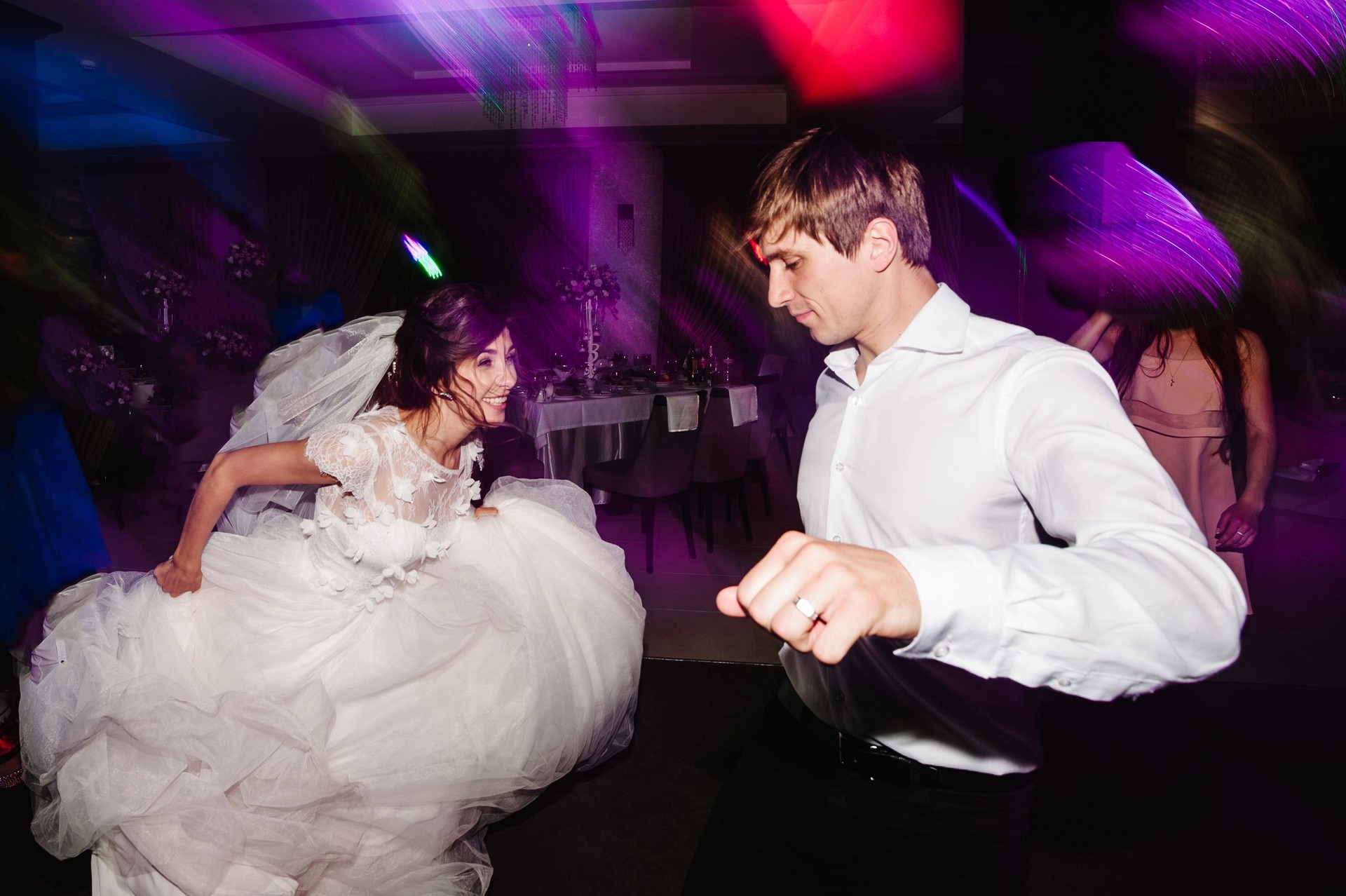 Wedding dance of newlywed and people. bride and groom dancing in restaurant. Wedding couple dancing in smoke and colored lights.